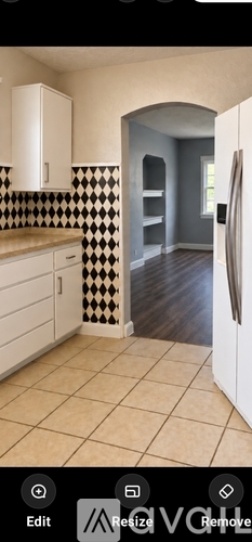 A kitchen with white cabinets and a black and white checkered backsplash.