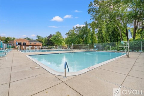 A large outdoor swimming pool surrounded by a fence and trees.