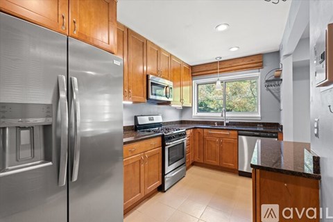 A kitchen with wooden cabinets and a stainless steel refrigerator.