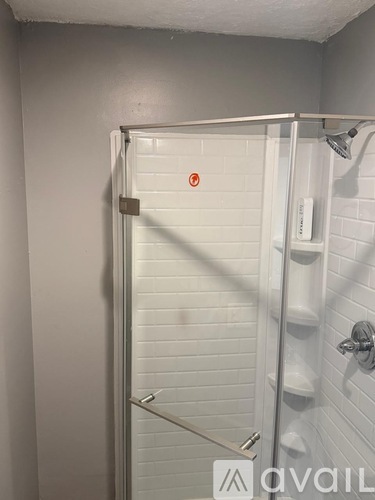 A white shower stall with a red dot on the door.