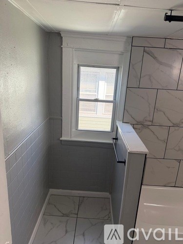 A bathroom with a window and tiled walls.