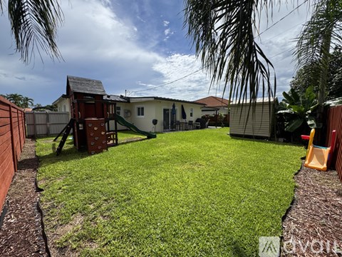 A backyard with a playground and a house in the background.