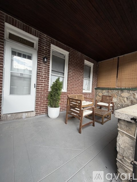 A patio with a white door, two windows, and a small tree in a white pot.