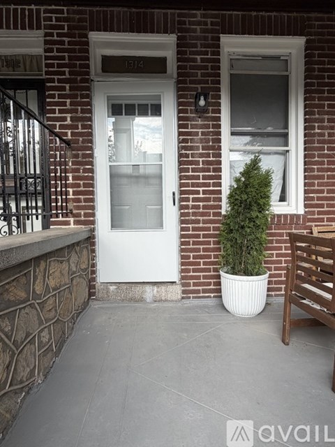 A white door is on the left side of a brick building.