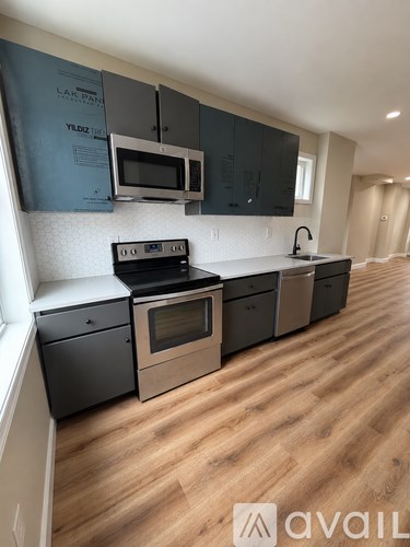 A kitchen with black cabinets and a wooden floor.