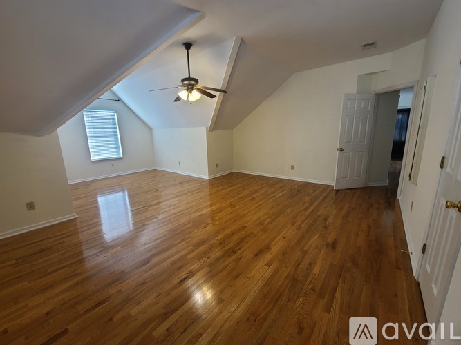 A room with wooden flooring and a ceiling fan.