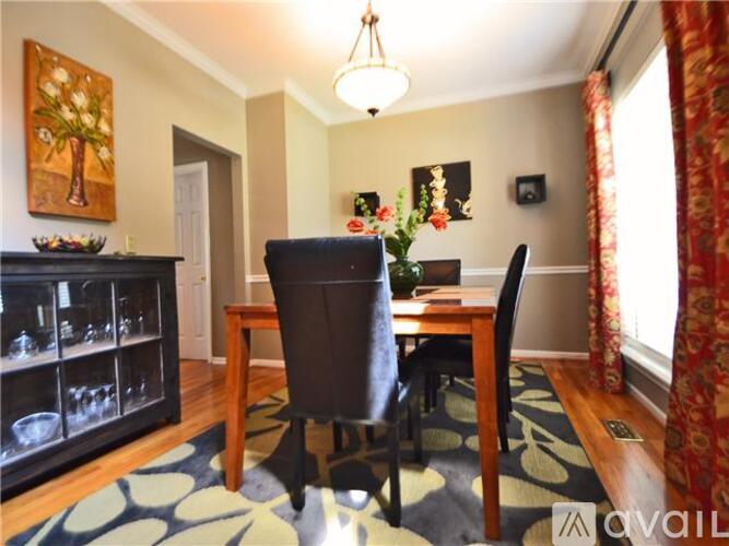 A dining room with a table, chairs and a painting on the wall.