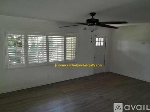 A room with a ceiling fan and a door with a window above it.