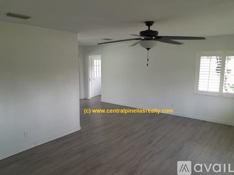 A room with a ceiling fan and wooden flooring.