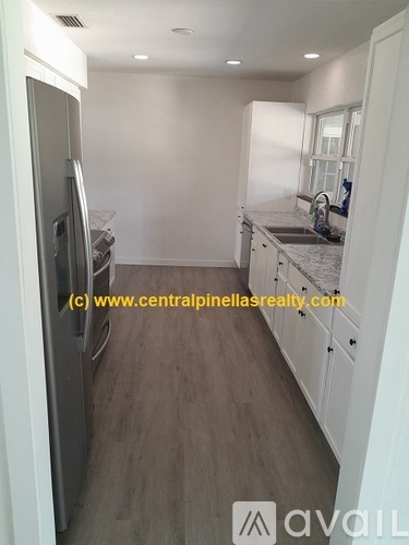 A kitchen with a refrigerator, sink, and cabinets.