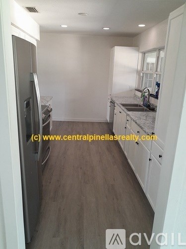 A kitchen with a refrigerator, sink, and cabinets.