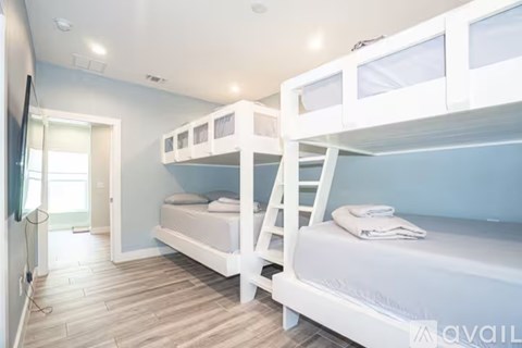 A bedroom with white bunk beds and a wooden floor.