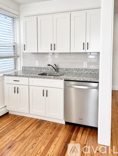 A kitchen with white cabinets and a granite countertop.