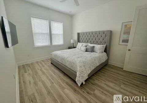 A bedroom with a large bed and wooden flooring.