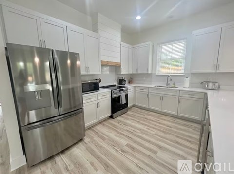 A modern kitchen with a stainless steel refrigerator and wooden flooring.