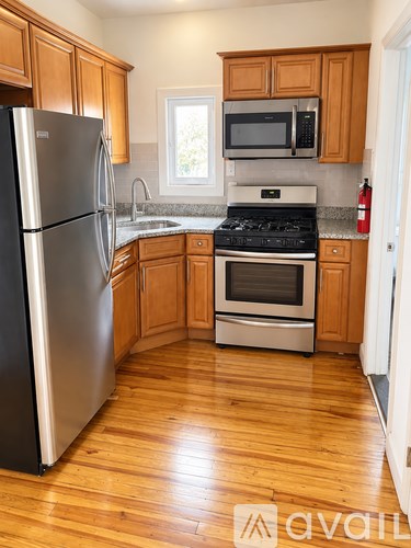 A kitchen with wooden cabinets and a stainless steel refrigerator.