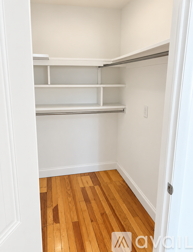A white pantry with shelves and wood floors.