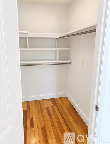 A white pantry with shelves and wood floors.