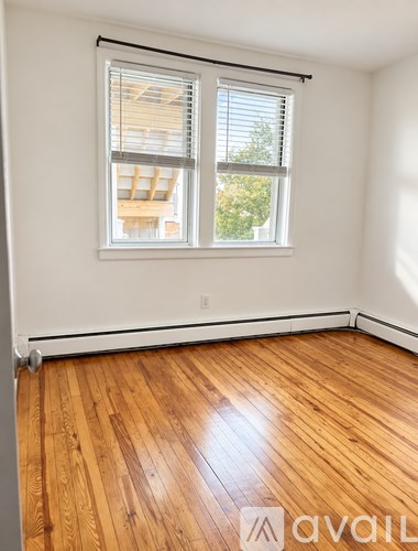 A room with wooden floors and a window with blinds.