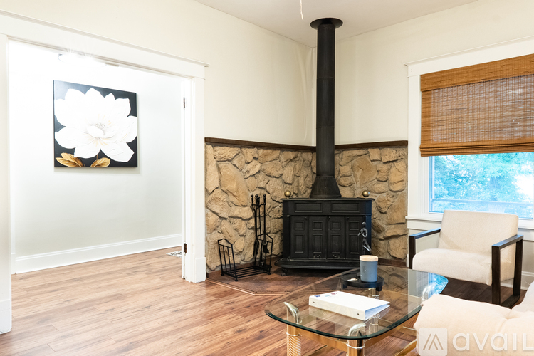 A living room with a wood stove and a painting of a flower on the wall.