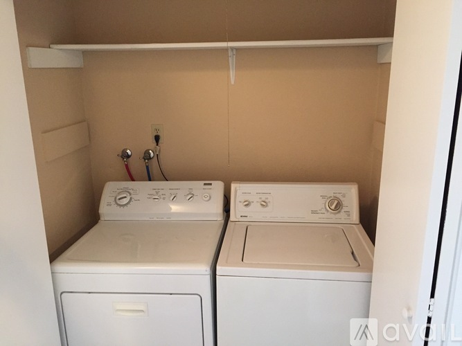 Two white front loading washing machines in a small laundry room.