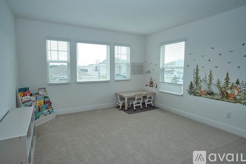 A room with a white couch, a white desk, and a wall mural of birds and trees.