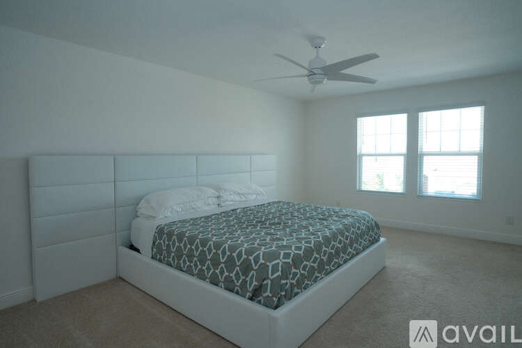 A bedroom with a bed and a ceiling fan.