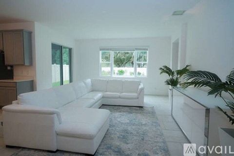 A living room with white furniture and a large window.