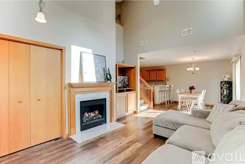 A living room with a fireplace and a dining area in the background.