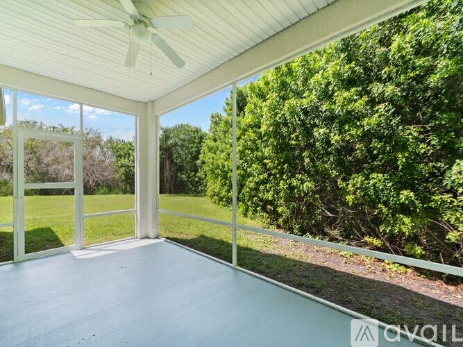 A sunny day in a room with a ceiling fan and sliding glass doors.