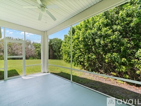 A sunny day in a room with a ceiling fan and sliding glass doors.