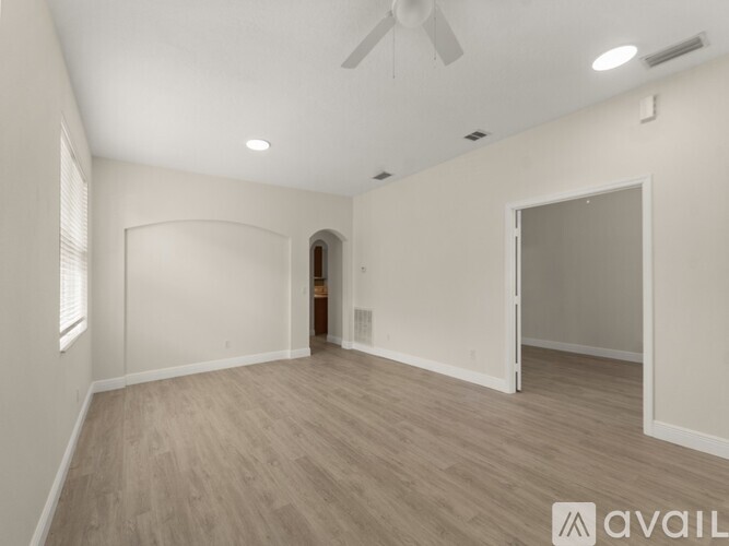 A spacious room with a fan and light-colored walls.