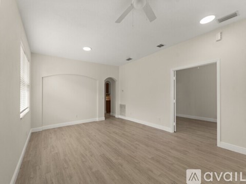 A spacious room with a fan and light-colored walls.