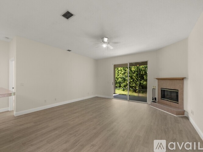 A spacious living room with a fireplace and sliding glass doors leading to a backyard.