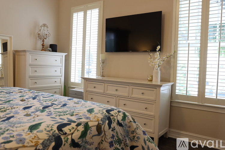 A bedroom with a bed, dresser, and television.