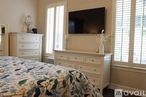 A bedroom with a bed, dresser, and television.