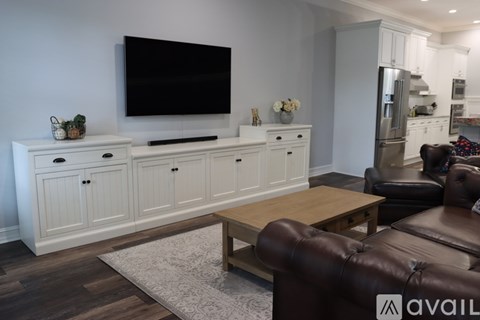 A living room with a brown leather couch and a white cabinet.