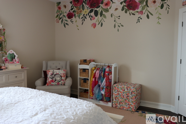 A floral wallpapered room with a chair and a bed.