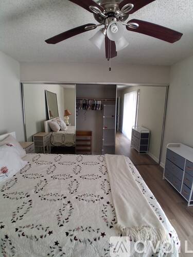 Bedroom with a bed, a dresser, a mirror, and a ceiling fan.
