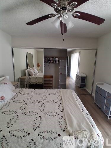 Bedroom with a bed, a dresser, a mirror, and a ceiling fan.