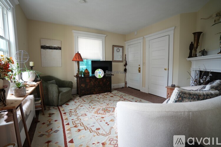 A living room with a patterned carpet and a fireplace.