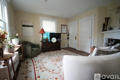A living room with a patterned carpet and a fireplace.