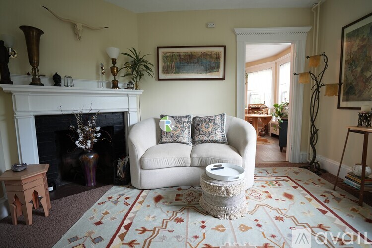 A living room with a fireplace, a couch, and a rug.