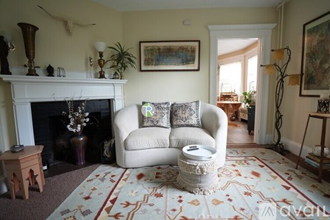 A living room with a fireplace, a couch, and a rug.