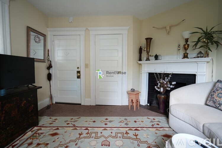 A living room with a fireplace and a rug on the floor.