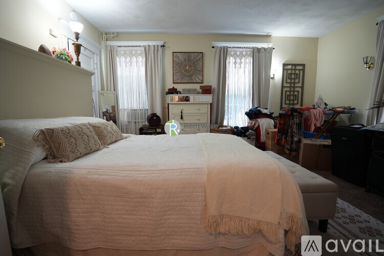 A bedroom with a large bed in the center and a dresser with a mirror above it.