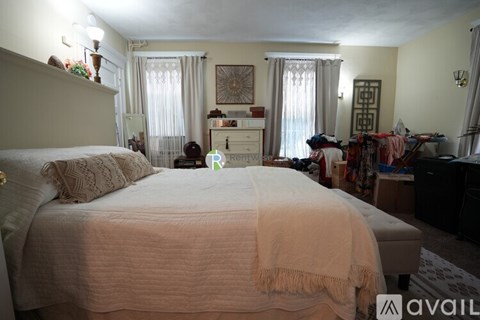 A bedroom with a large bed in the center and a dresser with a mirror above it.