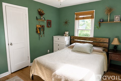 A bedroom with a bed, nightstand, and a window with blinds.