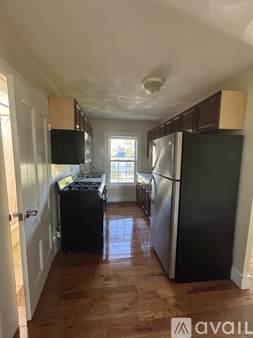 A kitchen with black appliances and wooden floors.