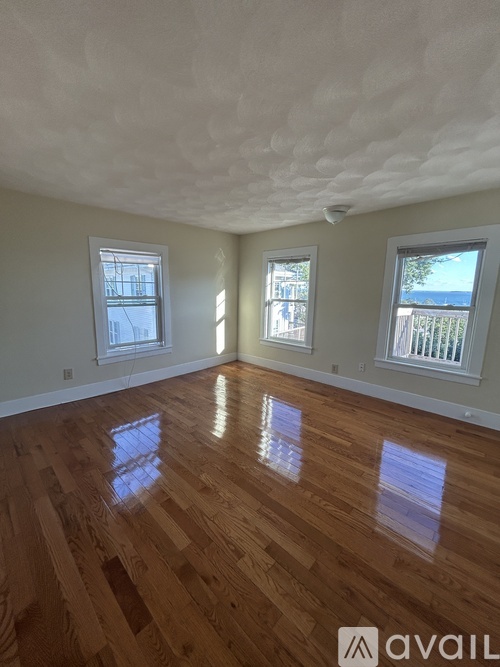 A room with wooden floors and three windows.